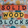 Colorful letter tiles spelling 'SOLID WOOD BLOCKS' on patterned background.