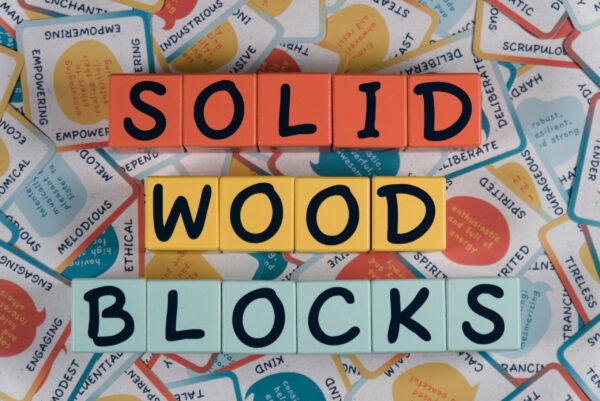Colorful letter tiles spelling 'SOLID WOOD BLOCKS' on patterned background.