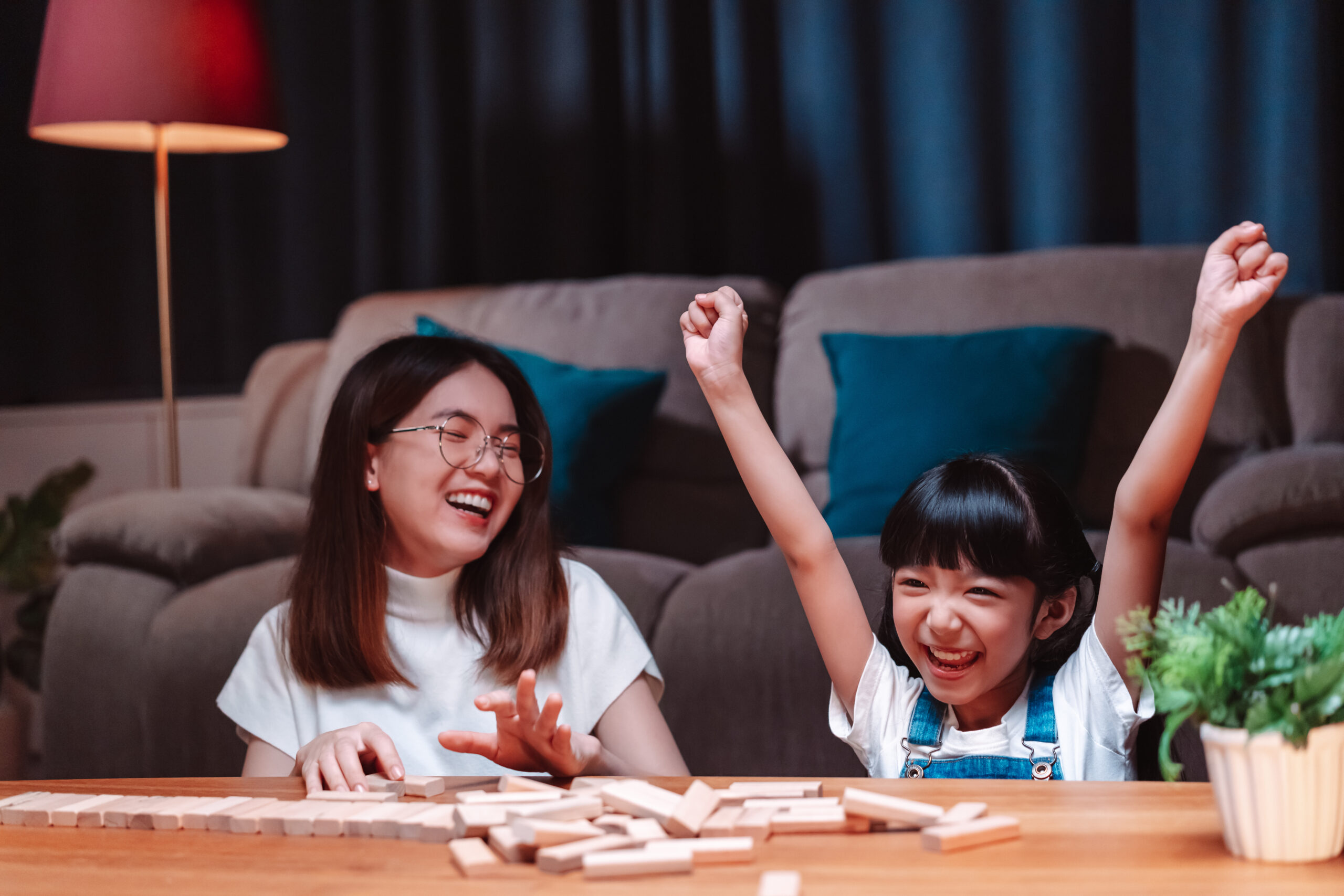 A joyful mother and daughter playing a game together at home.
